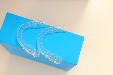 Transparent dental aligners on beige background, above view. Space for text