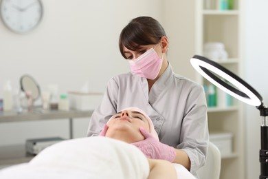 Photo of Cosmetologist making face massage to client in clinic