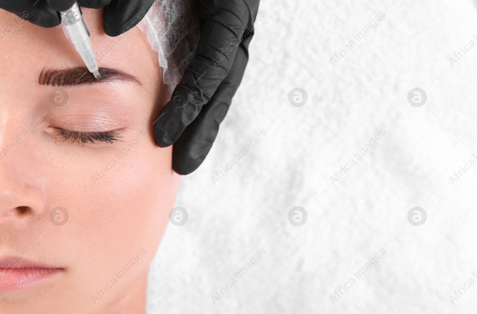 Photo of Young woman undergoing eyebrow correction procedure in salon, top view