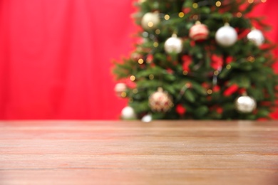 Wooden table near blurred decorated Christmas tree with lights on color background