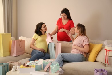 Photo of Happy pregnant women spending time together in living room after shopping