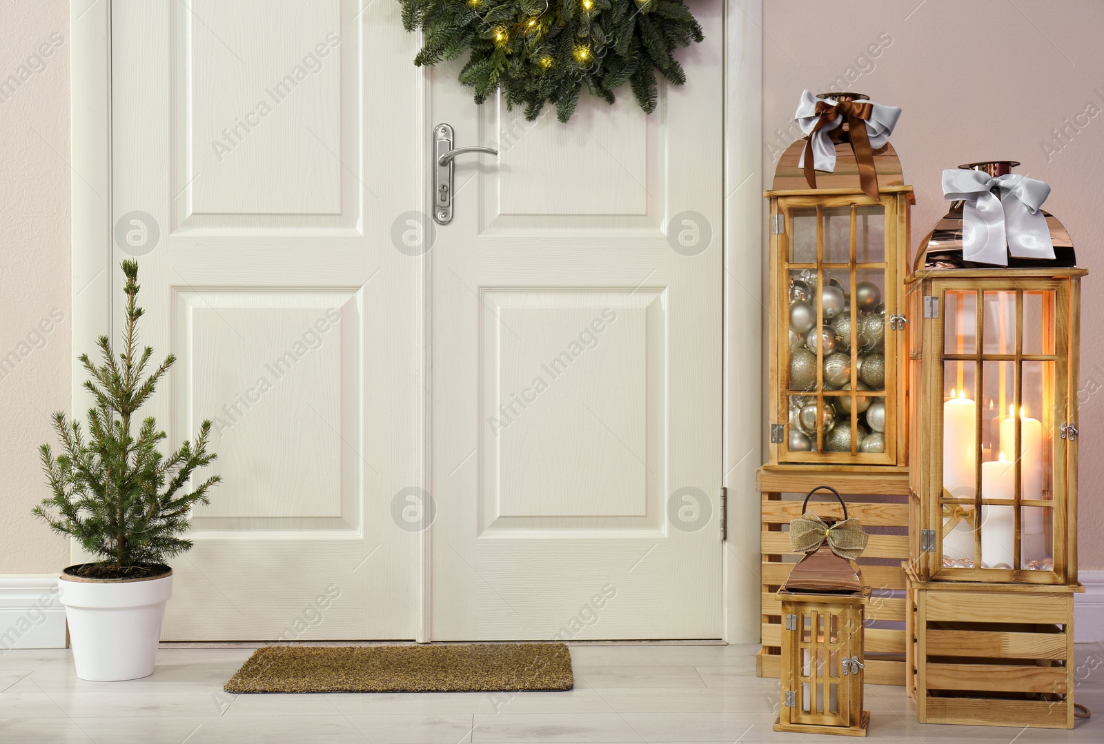 Photo of Beautiful Christmas lanterns and fir tree near entrance indoors