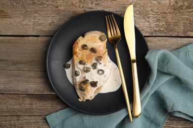 Photo of Delicious chicken fillet with capers and sauce on wooden table, top view