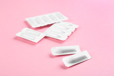 Photo of Suppositories on pink background, closeup view. Hemorrhoid treatment