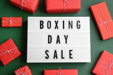 Lightbox with phrase BOXING DAY SALE and Christmas decorations on green background, flat lay
