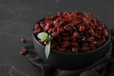 Photo of Bowl of dried cranberries on dark table, closeup