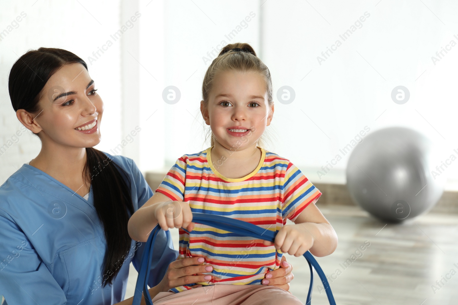 Photo of Orthopedist working with little girl in hospital gym