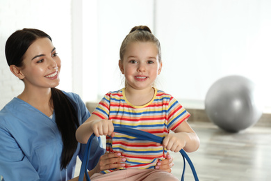 Photo of Orthopedist working with little girl in hospital gym