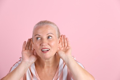 Photo of Mature woman with hearing problem on color background. Space for text