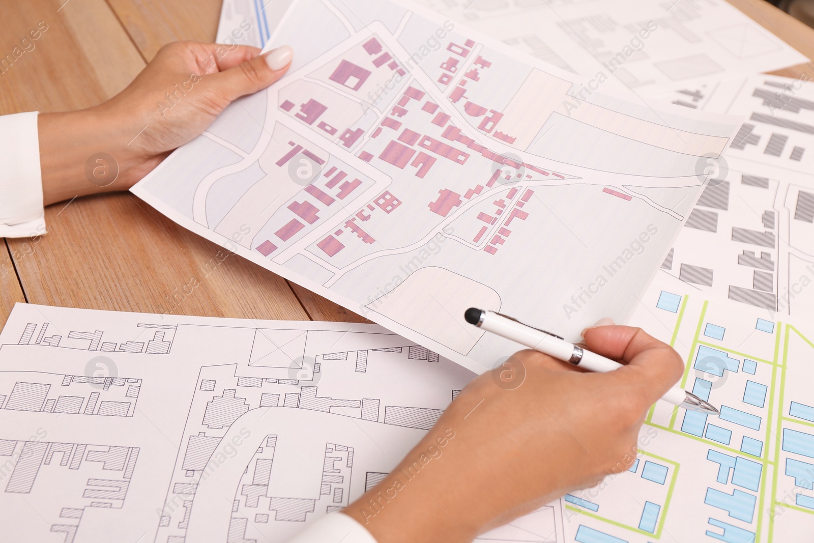 Photo of Professional cartographer working with cadastral map at wooden table, closeup