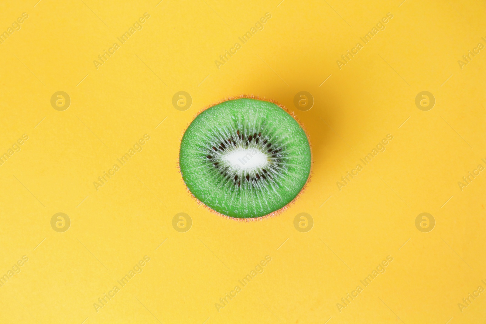 Photo of Cut fresh ripe kiwi on yellow background, top view