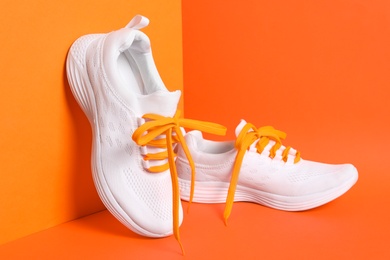 Photo of Stylish sneakers with shoe laces on orange background