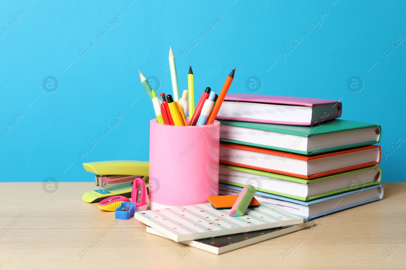 Photo of Composition with different school stationery on wooden table against light blue background. Back to school