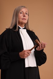 Senior judge with gavel on light brown background