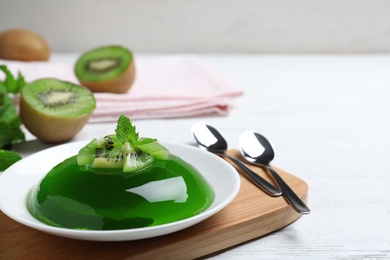 Delicious green jelly with kiwi slices on white wooden table