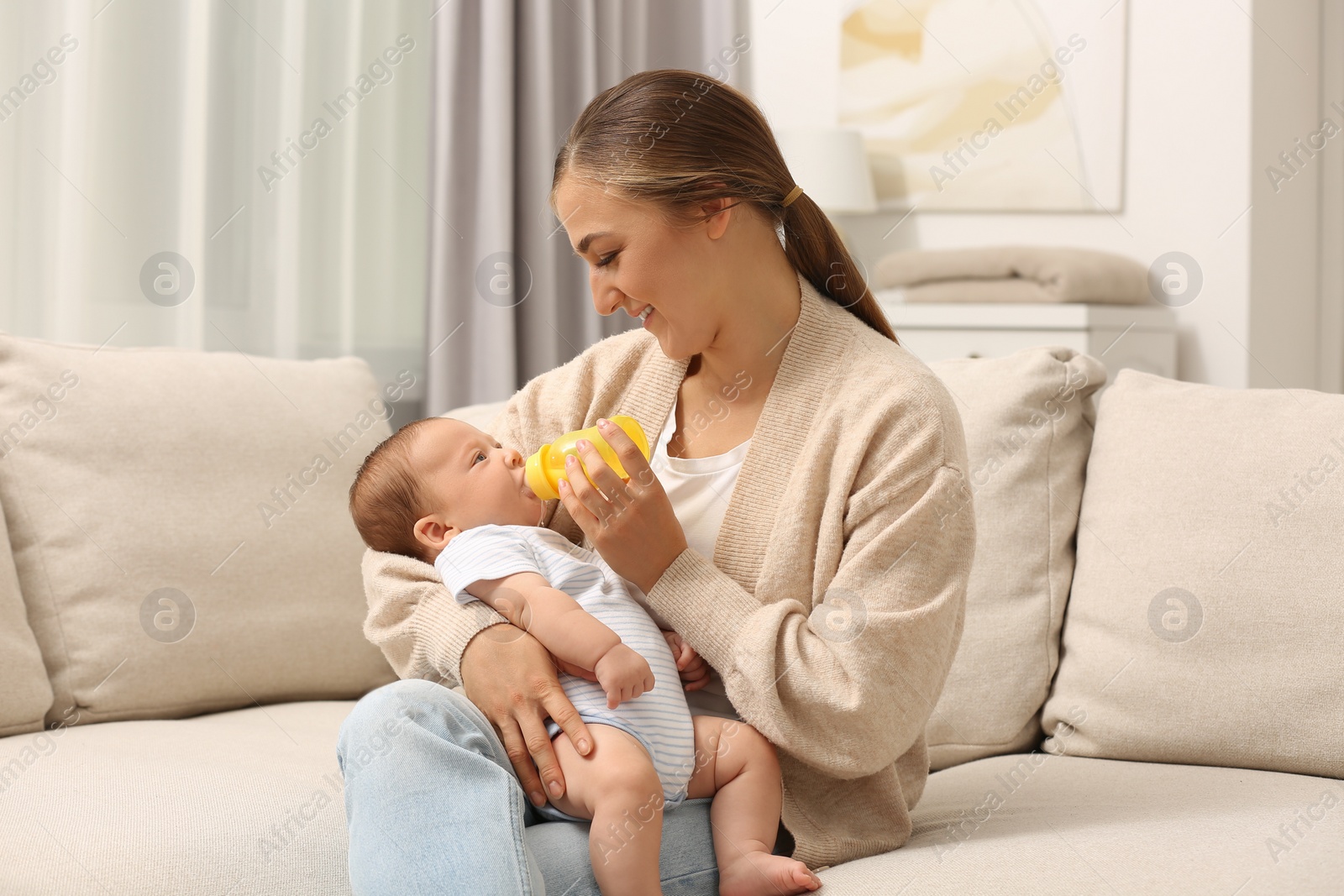 Photo of Mother feeding her cute child with infant formula indoors