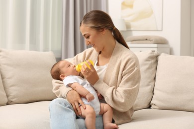 Photo of Mother feeding her cute child with infant formula indoors