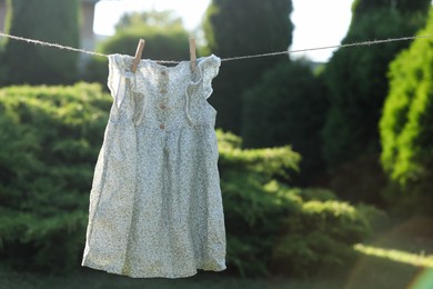 Photo of Dress drying on washing line near trees outdoors