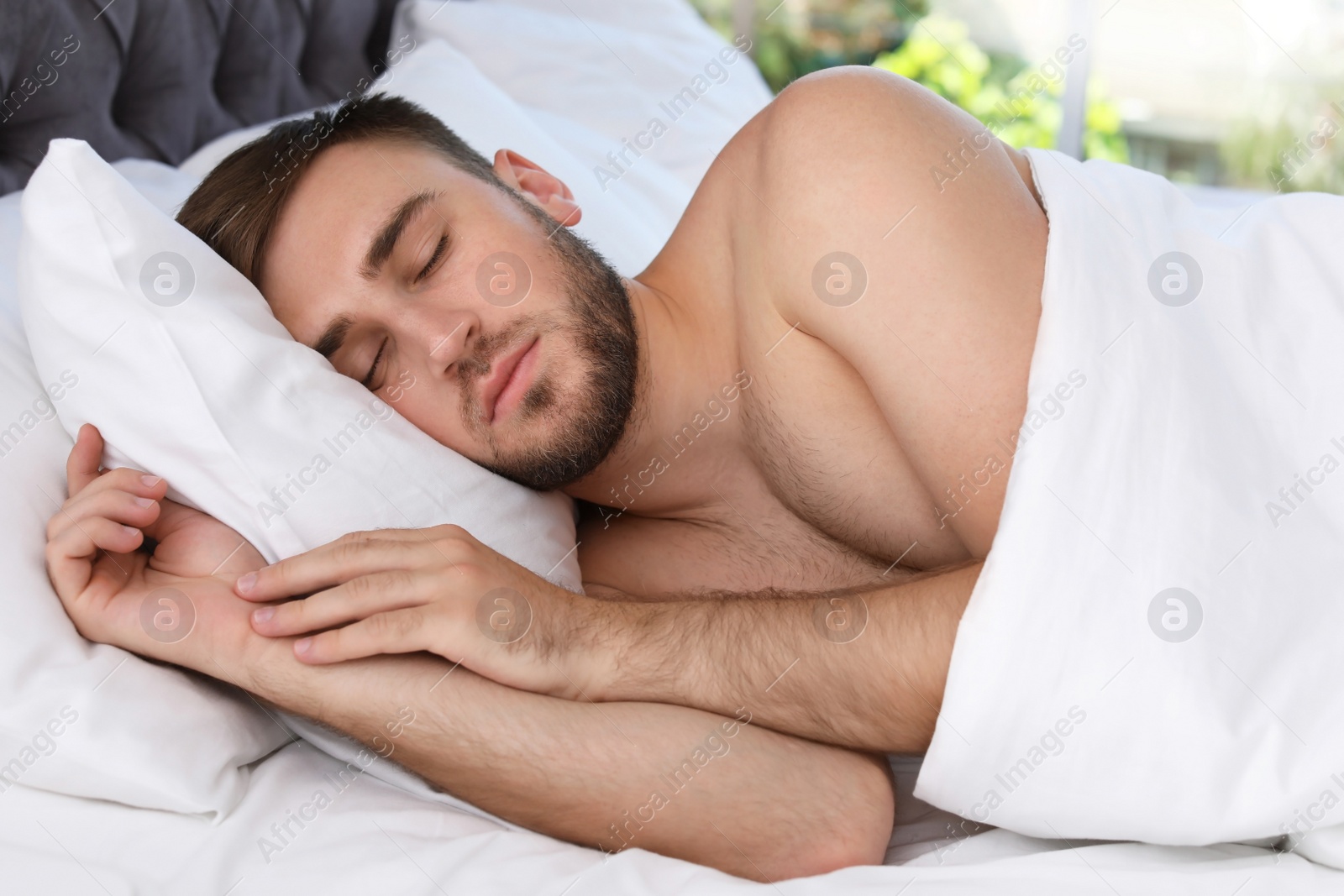 Photo of Young handsome man sleeping in bed at home. Early morning