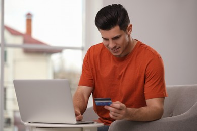 Man using laptop and credit card for online payment at home