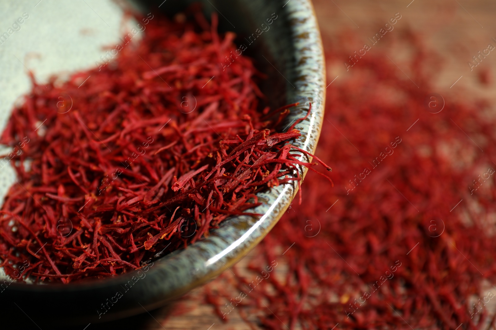 Photo of Aromatic saffron in bowl on table, closeup