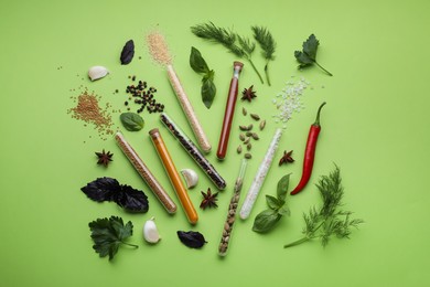 Photo of Flat lay composition with various spices, test tubes and fresh herbs on green background