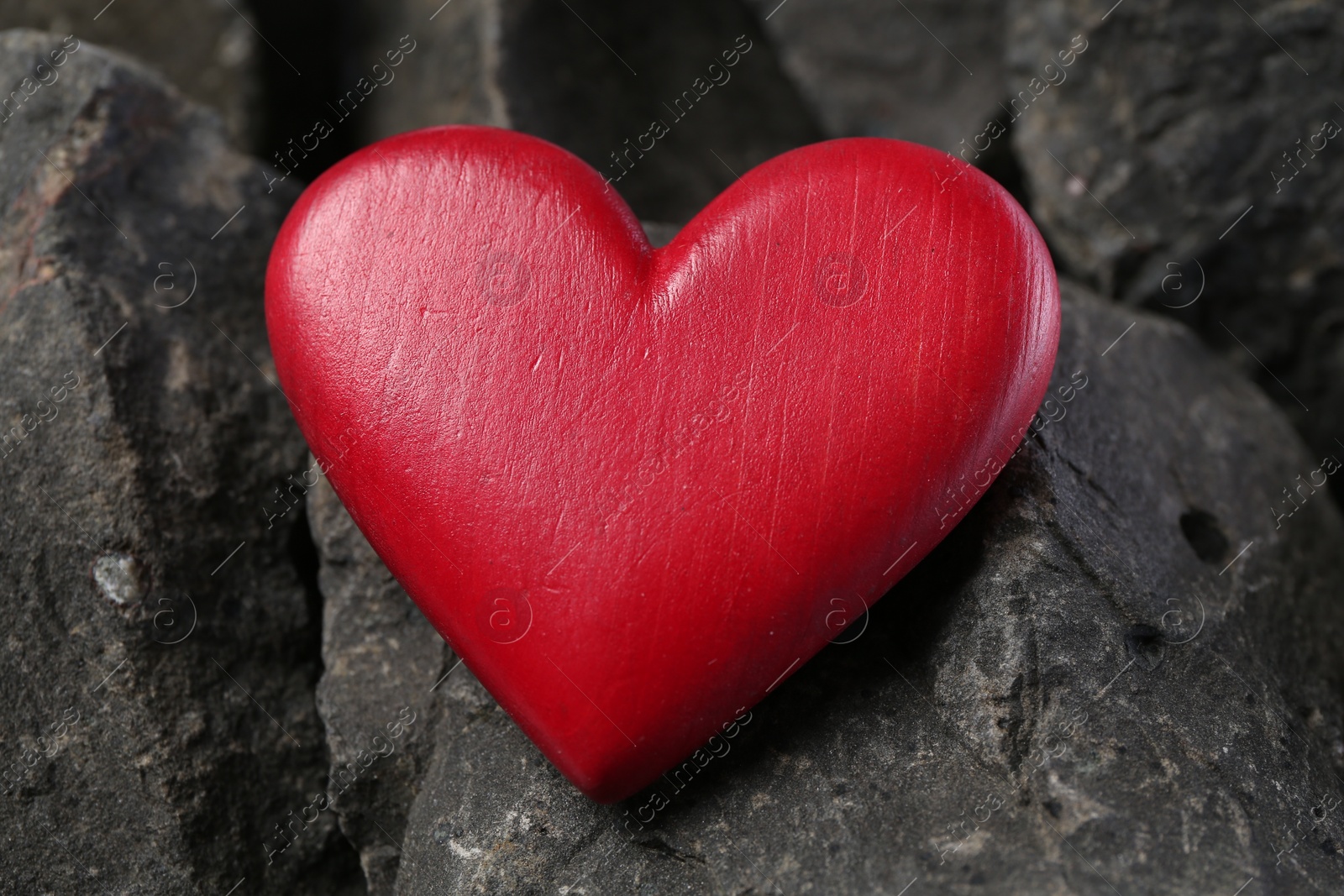 Photo of One red decorative heart on stones, closeup