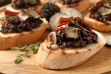 Delicious bruschettas with truffle sauce and sun dried tomatoes on wooden table, closeup