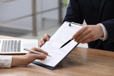 Businesspeople signing contract at table in office, closeup