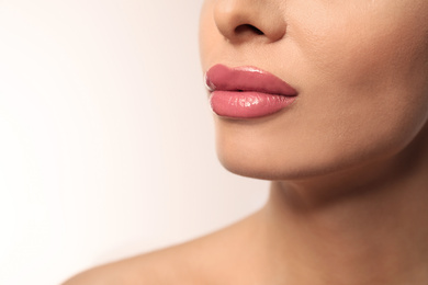 Woman with pink lipstick on light background, closeup