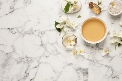 Photo of Flat lay composition with jasmine essential oil and fresh flowers on white marble table. Space for text