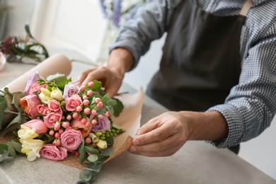 Photo of Male florist creating beautiful bouquet at table, closeup