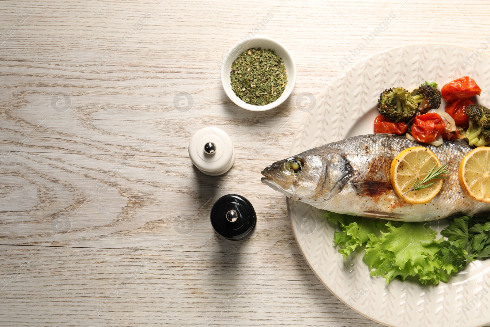 Photo of Delicious baked fish and vegetables served on wooden table, flat lay. Space for text