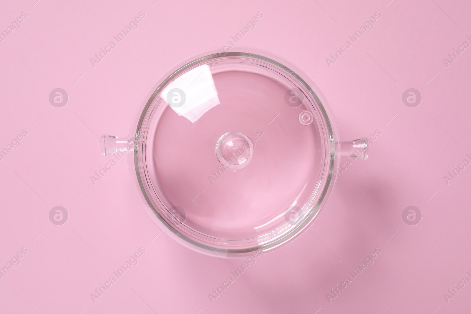 Photo of Glass pot with lid on pink background, top view