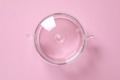 Glass pot with lid on pink background, top view