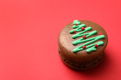 Beautifully decorated Christmas macaron on red background, space for text