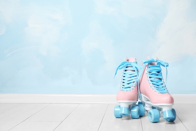 Vintage roller skates on floor near color wall. Space for text