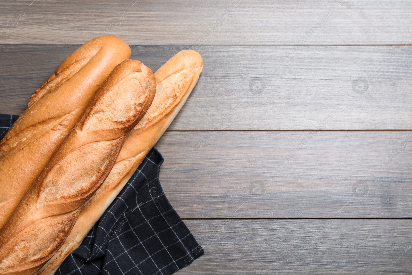 Photo of Tasty baguettes on wooden table, flat lay. Space for text