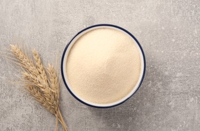 Photo of Uncooked organic semolina and spikelets on grey table, flat lay