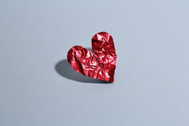 Red crumpled paper heart on gray background. Breakup concept