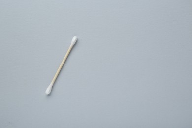 Photo of One wooden cotton bud on light grey background, top view. Space for text