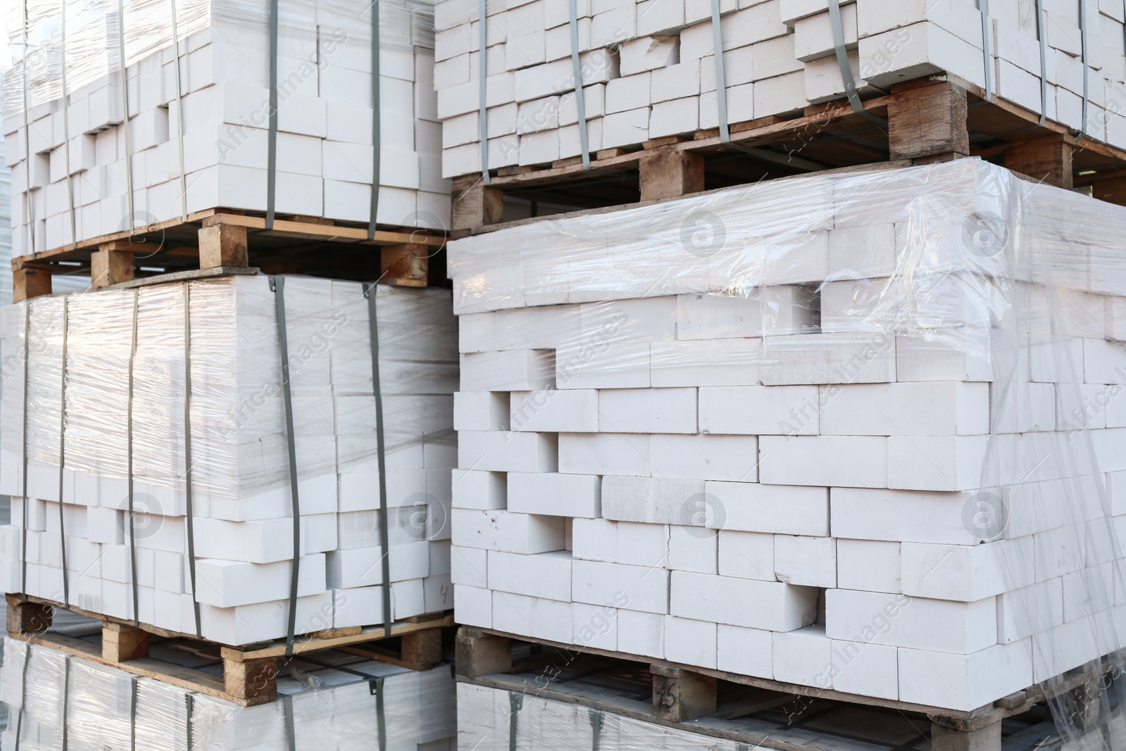 Photo of Pallets with white bricks outdoors. Building materials wholesale