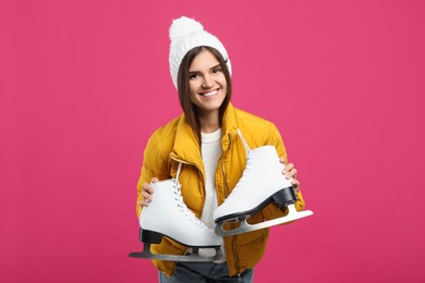 Happy woman with ice skates on pink background