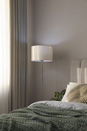 Stylish floor lamp and plant in bedroom. Interior element