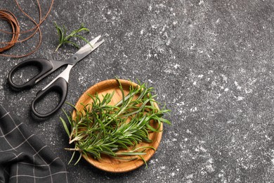 Photo of Fresh rosemary, scissors and threads on grey textured table, flat lay. Space for text
