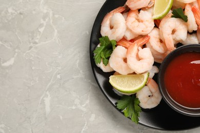 Photo of Tasty boiled shrimps with cocktail sauce, parsley and lime on light grey table, top view. Space for text