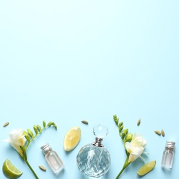 Flat lay composition with elegant perfumes on light blue background, space for text