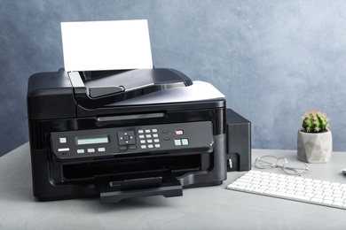 Photo of Modern printer with paper and computer keyboard on grey table