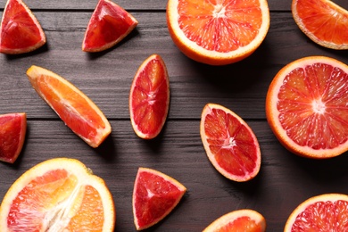 Photo of Cut fresh ripe red oranges on wooden table, flat lay