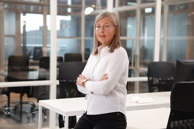 Photo of Confident woman with crossed arms in office. Lawyer, businesswoman, accountant or manager